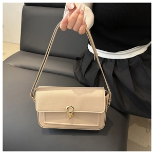 Detail of beige square bag with gold horseshoe clasp and textured lychee leather finish