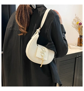 Bolso de media luna blanco con hebilla en S dorada y borla en modelo femenina