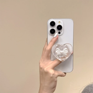 Close-up of a clear heart phone grip with white bow held on a smartphone