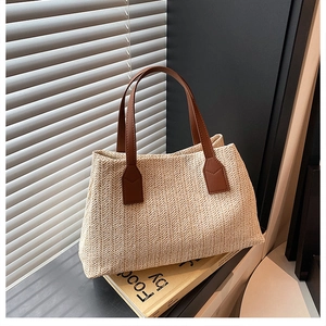 Detailed close-up view of a woven straw handbag featuring brown leather handles.