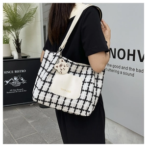 Detailed view of black and white plaid tote bag with fashion tag and cat charm