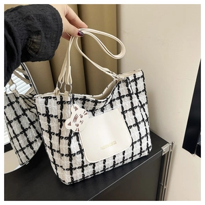 Detail of checkered tote bag featuring a leather pocket and cute white cat charm