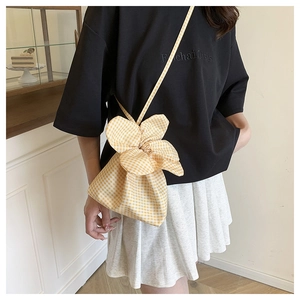 Detail of yellow gingham bucket bag with flower-shaped drawstring closure on a model
