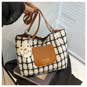 Detail of checkered tote bag featuring brown leather pocket and a cute tiger charm