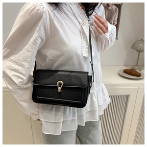 Close-up of black crossbody bag featuring a golden horseshoe buckle and pebbled leather texture