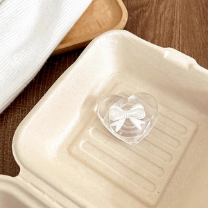 Close-up of heart-shaped phone grip with white 3D bow on a beige paper tray