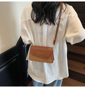 Close-up of brown leather and woven straw crossbody bag with golden buckle details