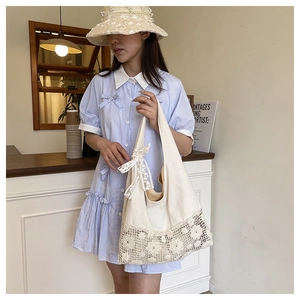 Asian model showcasing a large capacity hollow-out floral canvas bag in a cozy cafe.