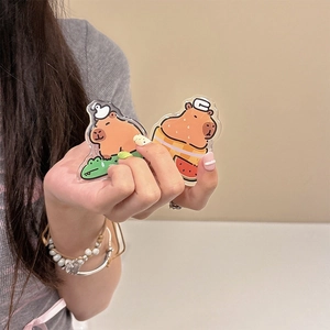Close-up of two cute acrylic capybara phone grips held by hand to show compact size