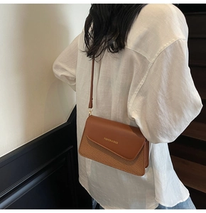 Detail of a brown leather and woven crossbody bag with gold Fashion & Bags lettering