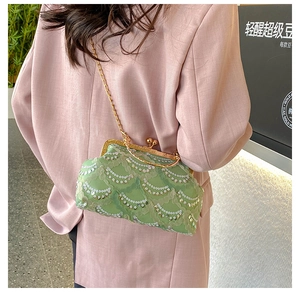 Detail of green sequin handbag with gold chain strap on a pink blazer outfit
