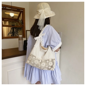 Hollow floral canvas shoulder bag with lace bow shown in a casual cafe setting