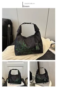 Detail of black embroidered bucket bag featuring green leaf patterns and knotted top handle
