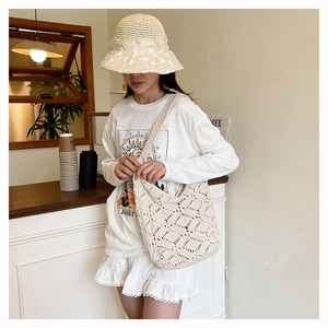 Detail of hollow diamond pattern on cream woven shoulder bag with boho tassel accents