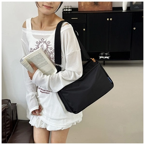 Detail einer schwarzen Messenger-Bag aus Nylon mit verstellbarem Gurt am Model getragen