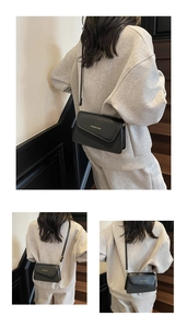 Detail of black crossbody bag featuring textured fiber finish and gold logo printing