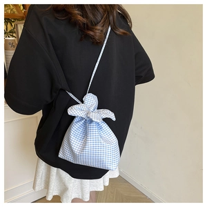 Blue and white gingham drawstring crossbody bag styled on a person in a casual setting
