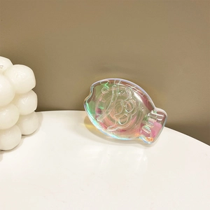 Detail of iridescent fish-shaped magnetic phone grip with 100 embossed on clear resin
