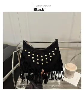 Detail view of black suede tassel hobo bag with gold rivets on a modern chair
