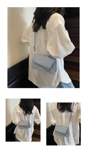 Close-up of light blue flap bag with woven texture and gold logo on white shirt backdrop