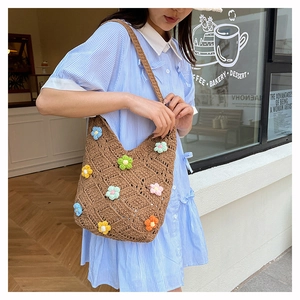 Close-up of handmade knit tote bag with colorful 3D floral accents in outdoor setting