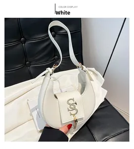 Detalle de bolso hobo blanco con borla dorada y textura de cuero sobre seda blanca
