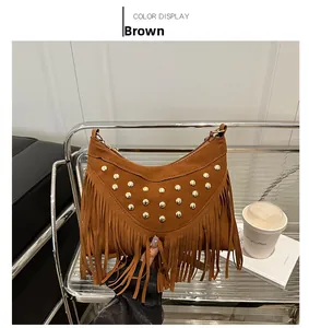 Close-up of brown suede saddle bag featuring gold rivets and long fringe details
