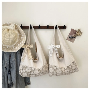 Close-up detail of hollow lace floral embroidery and bow on a beige canvas shoulder bag
