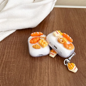 Macro view of clear AirPods case with 3D miniature bread charms and sweet paper bag detail