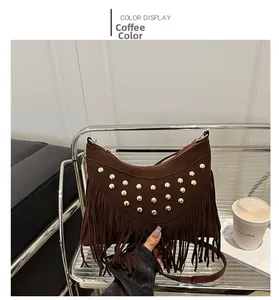 Close-up of brown suede saddle bag featuring golden studs and long fringe tassels
