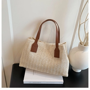 Korean style woven straw handbag with brown leather handles on a minimalist background