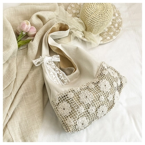Detail view of floral crochet patterns and a lace bow on a beige canvas shoulder bag.