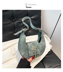 Detalle de bolso medialuna verde vintage con logotipo metálico y borla elegante