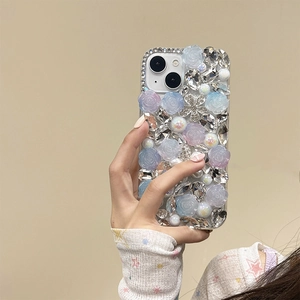 Detailed view of luxury phone case with blue roses, rhinestones and pearls on soft beige background