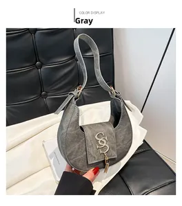 Detalle de bolso hobo de mezclilla gris con logo en S dorado y elegante borla colgante