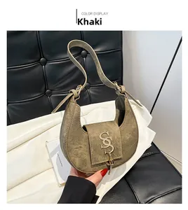 Detalle de bolso medialuna caqui en ante con hebilla metálica dorada de la letra S logo