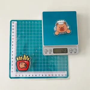 Macro view of two cartoon capybara acrylic phone stands on a scale weighing 12.1g