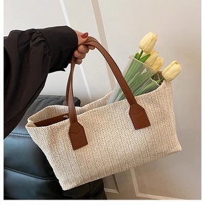 Stylish hand-woven straw tote bag featuring brown leather handles and yellow tulips