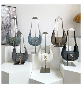 Row of velvet hobo bags in assorted colors with metal tassels and logo on silver stands