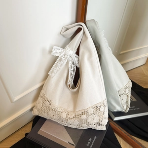Elegant cream canvas tote bag featuring intricate lace flower detail and bow accent