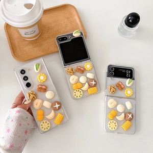 Detail of transparent phone case featuring 3D realistic nut and vegetable charms on a tray
