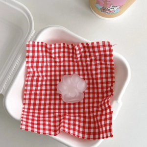 Close-up of translucent pink cat paw phone grip with heart-shaped pad on checkered paper