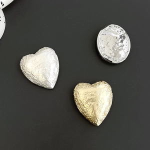 Close-up of heart-shaped metal phone grips with unique wrinkled foil texture in gold and silver