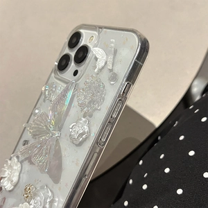 Macro detail of 3D pearlescent butterfly and floral decorations on iPhone 16 Pro Max case
