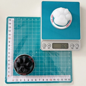 Detail shot of cat paw phone stand weighing 36.5g on a scale for size verification