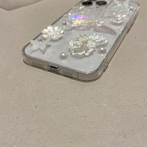 Macro detail of 3D pearl butterfly and flower ornaments on a transparent iPhone case
