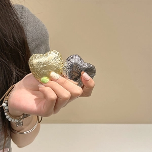 Detail of gold and silver heart-shaped phone grips with metallic foil texture on hand