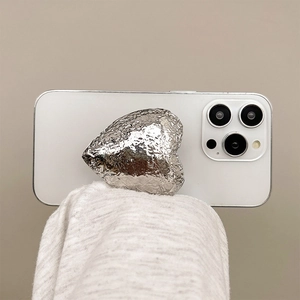 Macro shot of silver heart phone grip with crushed foil texture on white smartphone
