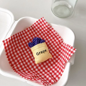 Detail of creative grape-shaped expandable phone grip on a red checkered paper base
