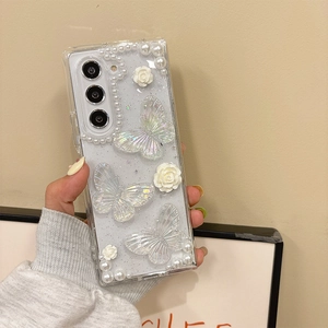Détail d'une coque scintillante avec papillons 3D, fleurs de camélia et perles